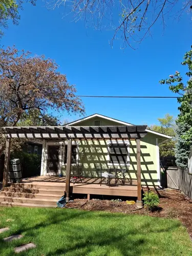 Backyard patio with pergola attached to a green house, highlighting curb appeal after roof replacement in Longmont
